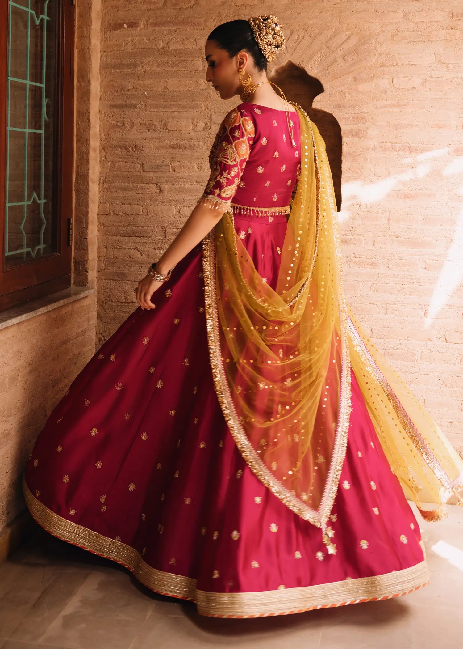 Fuschia Anaya magenta lehnga choli with traditional resham and gota embroidery paired with a contrasting olive-green dupatta for festive elegance.