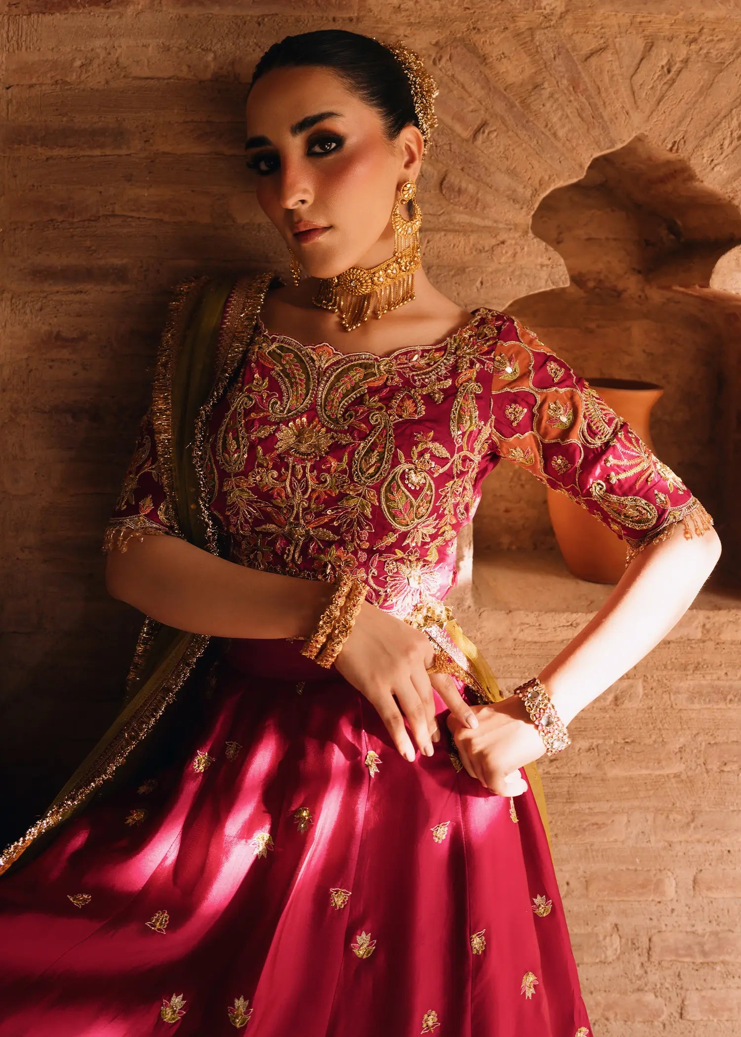 Fuschia Anaya magenta lehnga choli with traditional resham and gota embroidery paired with a contrasting olive-green dupatta for festive elegance.
