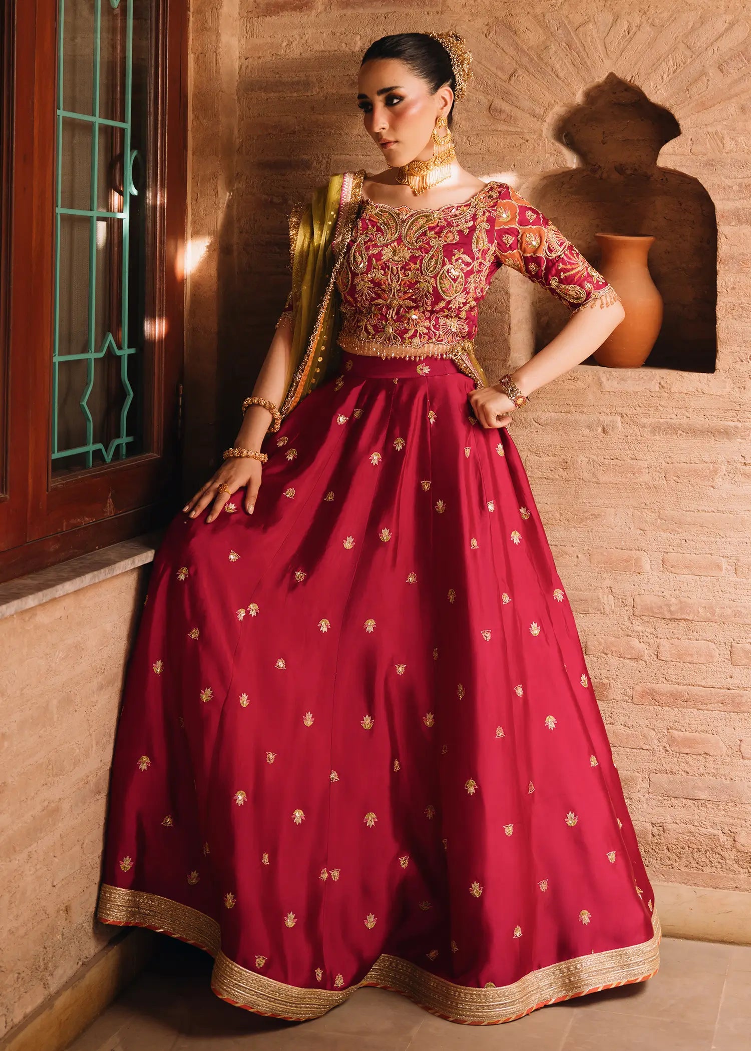 Fuschia Anaya magenta lehnga choli with traditional resham and gota embroidery paired with a contrasting olive-green dupatta for festive elegance.
