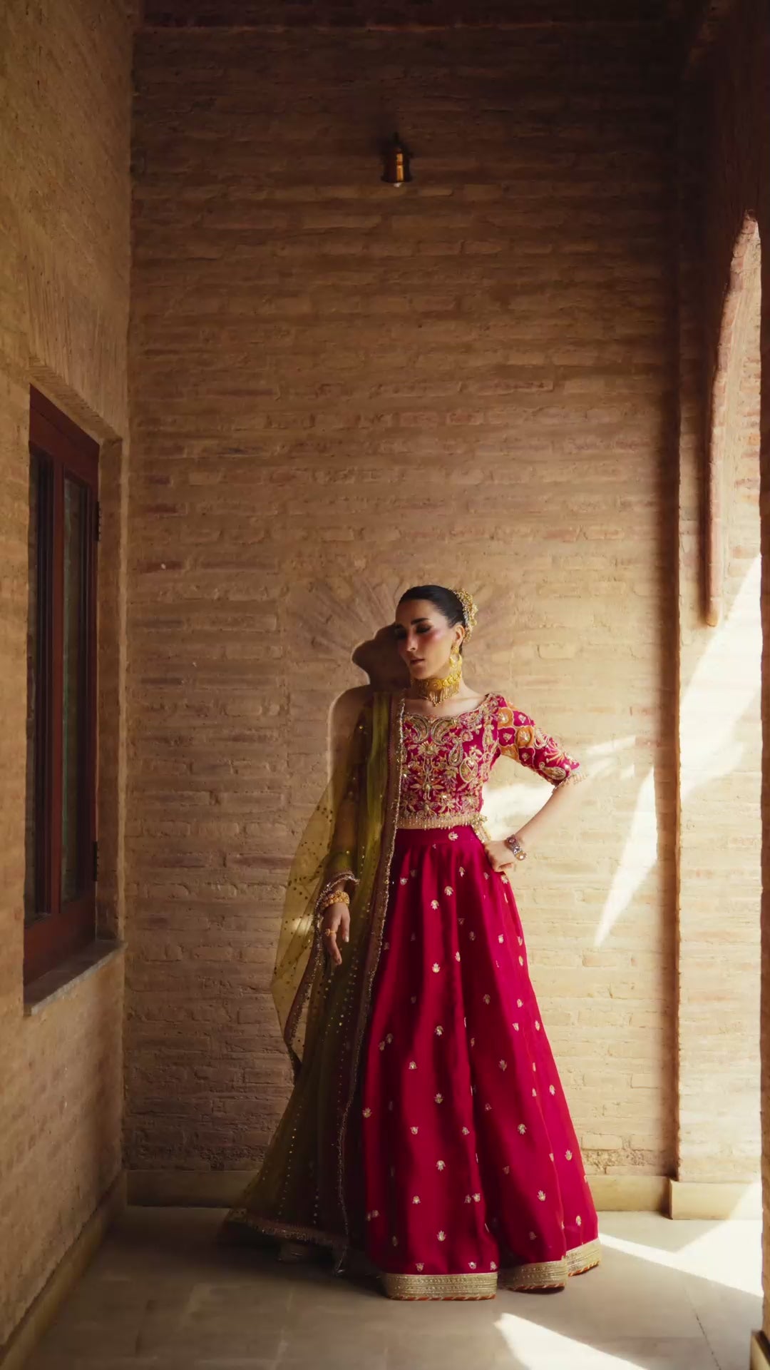 Fuschia Anaya magenta lehnga choli with traditional resham and gota embroidery paired with a contrasting olive-green dupatta for festive elegance.
